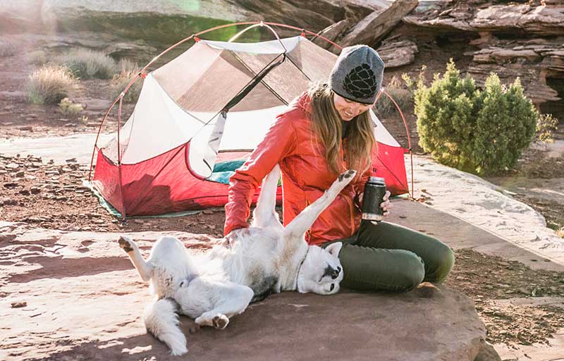 Woman Playing with Dog near Campsite with Red Tent